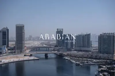 a bridge over a river in a city with buildings at Cozy 1BR Apartment with Balcony in Business Bay in Dubai