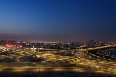 a night view of a freeway interchange with a city at Stylish Studio Near Dubai Academic City in Dubai