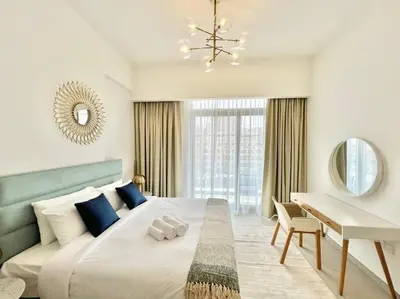 a white bedroom with a large bed and a desk at Waves - Comfortable JVC Apt with Balcony and Maids Room in Dubai