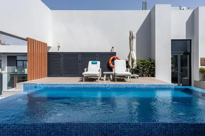 two chairs and a swimming pool in a house at Waves - Comfortable JVC Apt with Balcony and Maids Room in Dubai