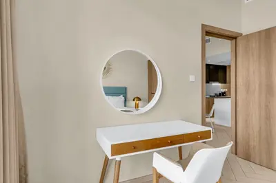 a white room with a table and a mirror at Waves - Comfortable JVC Apt with Balcony and Maids Room in Dubai