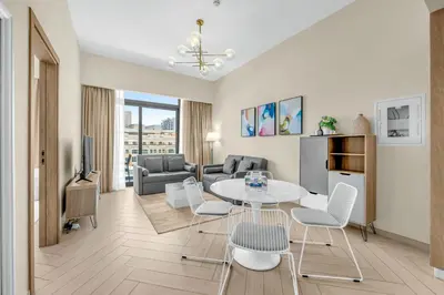 a living room with a table and chairs at Waves - Comfortable JVC Apt with Balcony and Maids Room in Dubai