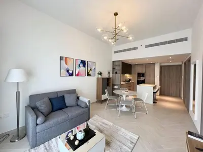 a living room with a couch and a table at Waves - Comfortable JVC Apt with Balcony and Maids Room in Dubai