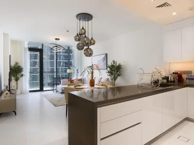 a kitchen with white cabinets and a living room at Amazing 2BDR with Lagoon view in District One 13 Al Merkadh in Dubai