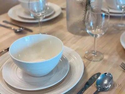 a bowl on a plate on a table with wine glasses at Elevated Living at The Bay - Canal & Khalifa Views in Dubai