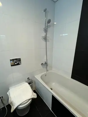 a white bathroom with a tub and a toilet at Brand New JVC 1 bed - sleeps 4 in Dubai
