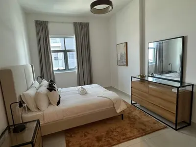 a bedroom with a bed and a dresser and a mirror at Brand New JVC 1 bed - sleeps 4 in Dubai