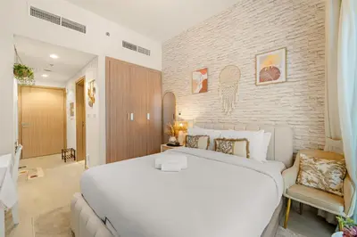 a bedroom with a large white bed and a brick wall at Lovely Apt Near The Burj with Pool, Gym & BBQ Area in Dubai