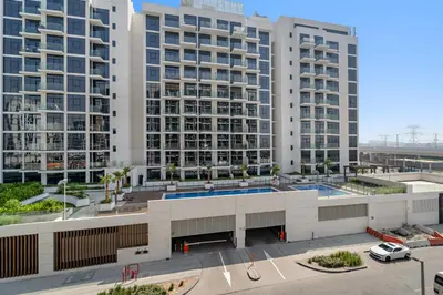an apartment building with two large buildings in the background at Lovely Apt Near The Burj with Pool, Gym & BBQ Area in Dubai