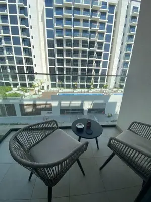 a balcony with a table and chairs and a large building at Lovely Apt Near The Burj with Pool, Gym & BBQ Area in Dubai