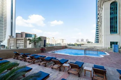 a patio with chairs and a swimming pool on a building at Upgraded Stylish Living with Private Steam Room in Dubai