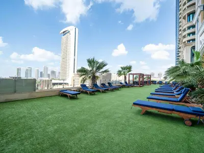 a row of blue lounge chairs on the roof of a building at Upgraded Stylish Living with Private Steam Room in Dubai