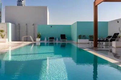 a large pool with blue water in a building at Waves - Refined Studio with Balcony & City Views in Luma21 in Dubai