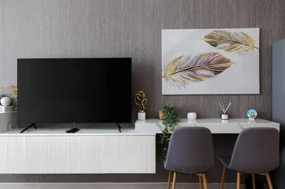 a living room with a television on a white cabinet at Waves - Refined Studio with Balcony & City Views in Luma21 in Dubai