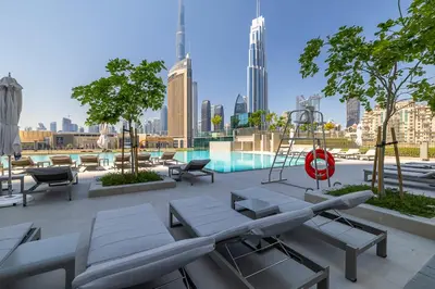 a patio with tables and chairs and a pool at Beautiful Home with Full Burj View in Downtown in Dubai