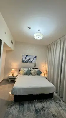 a bedroom with a large bed and two tables with lamps at Home away from home in Dubai