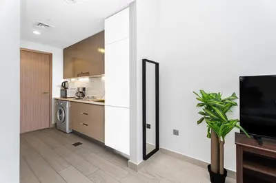 a kitchen with white walls and a tv in a room at Escape24 Studio at Azizi Riviera near Business Bay in Dubai