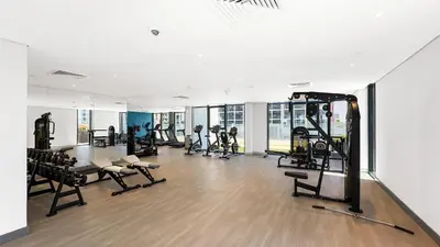 a gym with tread machines and people in the background at Escape24 Studio at Azizi Riviera near Business Bay in Dubai