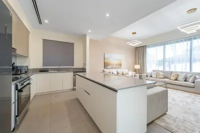 a kitchen with white cabinets and a living room at NewArabian Sidra1 -4 BR & Maid in Dubai