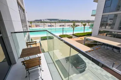 a balcony with two chairs and a view of a pool at Stunning 1BR Retreat with Crystal Lagoon Views! in Dubai