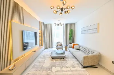 a living room with a couch and a tv at Stunning 1BR Retreat with Crystal Lagoon Views! in Dubai