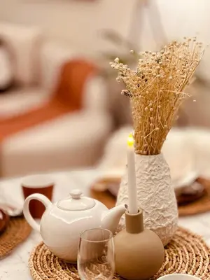 a table with a tea pot and a candle and a vase at Paramount Midtown I Sky High Luxury 2BR Apartment with Burj Khalifa View & Highest Infinity Pool I Down Town Dubai in Dubai