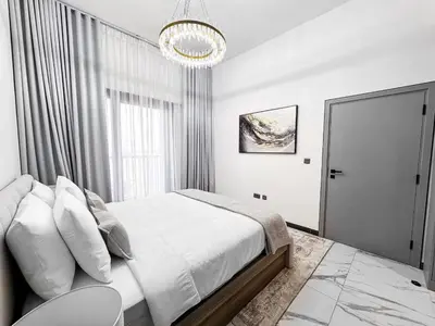 a white bedroom with a bed and a chandelier at Upgraded 1BDR APT in Mag 930 , AL Merkadh Dubai in Dubai