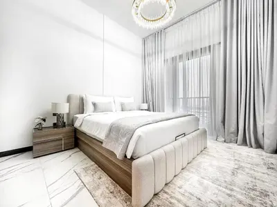 a white bedroom with a large bed and a chandelier at Upgraded 1BDR APT in Mag 930 , AL Merkadh Dubai in Dubai