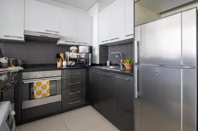 a kitchen with white cabinets and a stainless steel refrigerator at Frank Porter - Silverene Tower B in Dubai