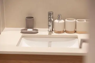 a bathroom sink with two cups and a faucet at Cozy 1 - Bedroom Retreat in DHE in Dubai