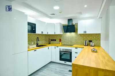a kitchen with white cabinets and a wooden counter top at Luxury Escapes - Elegant 3BR Apt with 4 Balconies in 29 Blvd in Dubai