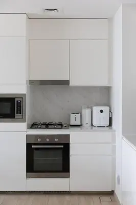 a kitchen with white cabinets and a stove top oven at Palace Residence Dubai Creek Harbour 1 Bd Apt in Dubai