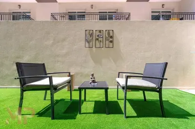 two chairs and a table on the grass at Marco Polo - Experience elegant living in JVC Dubai in Dubai