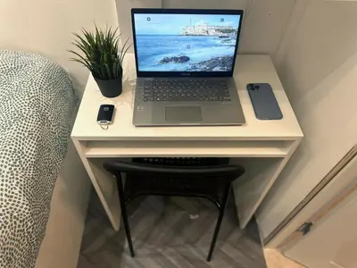 a laptop computer sitting on a desk next to a chair at The Flex Partition Room Near Mall of the Emirates in Dubai