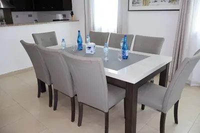 a dining room table with chairs and blue bottles on it at Specious 2BR VILLA WITH MAIDROOM AND HUGE GARDEN IN JVT DUBAI in Dubai