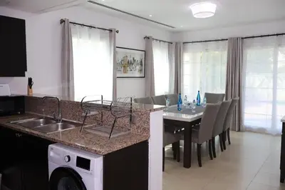 a kitchen and dining room with a table and a washing machine at Specious 2BR VILLA WITH MAIDROOM AND HUGE GARDEN IN JVT DUBAI in Dubai