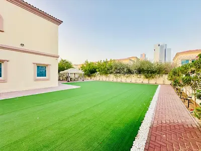 a green lawn in the middle of a building at Specious 2BR VILLA WITH MAIDROOM AND HUGE GARDEN IN JVT DUBAI in Dubai