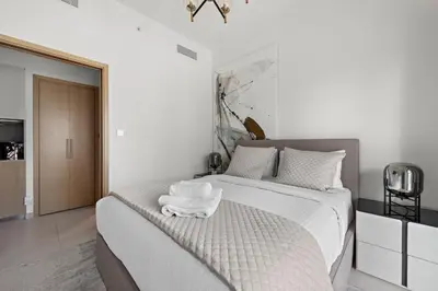 a white bedroom with a bed with two towels on it at Luxurious 1-Bedroom Apartment in Dubai