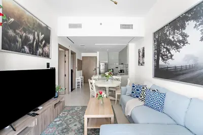 a living room with a blue couch and a tv at Elegant 1-Bedroom Apartment in Dubai