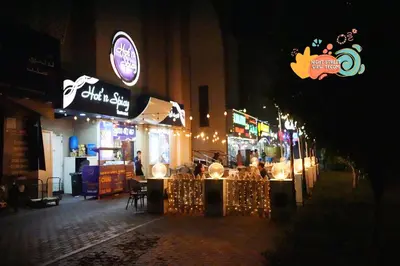 a street with a restaurant at night with lights at Vista Partition Room in Tecom Near Internet City Metro in Dubai