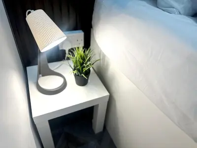 a bedside table with a lamp and a plant on it at Cove Partition Room in Tecom Near Internet City Metro in Dubai