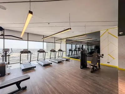 a gym with a row of treadmills and ellipticals at Stylish 1-Bedroom in Prime Business Bay Aykon C in Dubai