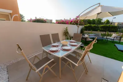 a table with chairs and an umbrella on a patio at Luxury Villa in Ranches 1, on Pool and Park in Dubai