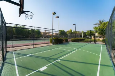 a tennis court with a net and a basketball hoop at Luxury Villa in Ranches 1, on Pool and Park in Dubai