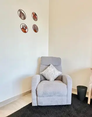 a chair in a living room with plates on the wall at Cozy Retreat, Relax and Explore in Dubai