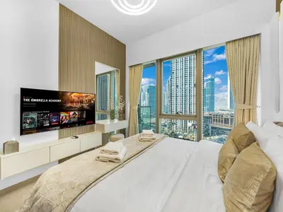 a bedroom with a large bed with a tv and large windows at SmartStay at Grande Signature - Downtown Dubai City Views - Brand New Luxury Apartments in Dubai