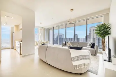 a living room with a large couch and large windows at Modern Home on 33rd Floor in Dubai Creek in Dubai