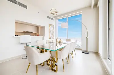 a dining room with a glass table and white chairs at Modern Home on 33rd Floor in Dubai Creek in Dubai