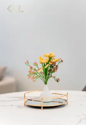 a vase with flowers on a plate on a table at Luxury 2-Bed in Paramount Midtown Hotel Full Burj Khalifa Views 64th Floor Pool & Burj Views in Dubai