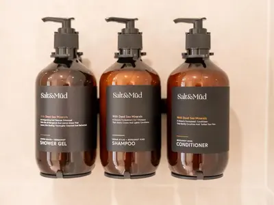 a group of three shampoo bottles in a shelf at Brand New Downtown unit! Bvlgari World Island View in Dubai